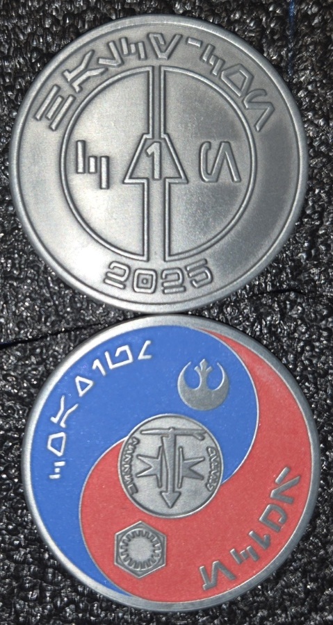 Two faces of a round 2025 commemorative coin, one silver-toned and one with blue and red enamel