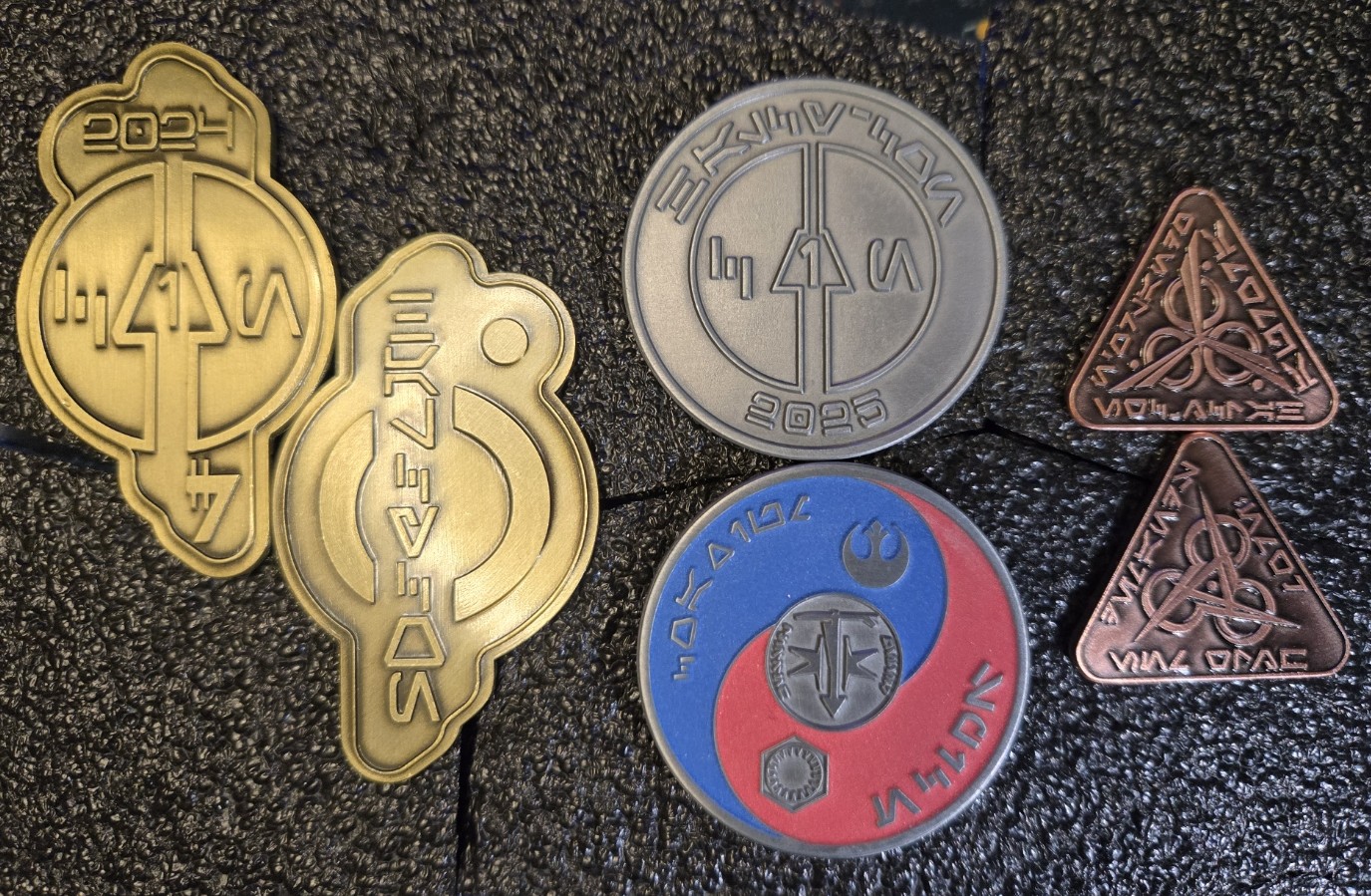 Collection photograph showing 2024 shaped credits, 2025 round coin, and Aurora triangular pieces